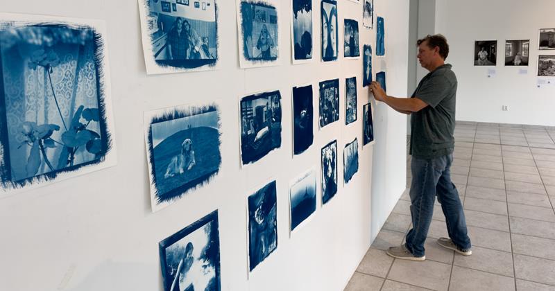 Jon Cox placing cyanotypes on wall to display